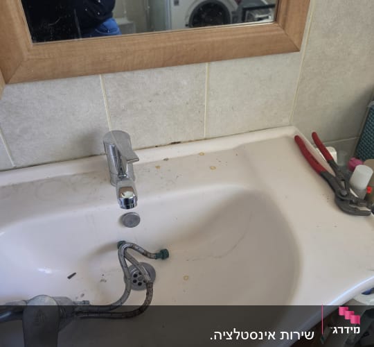 כיור עם ברז וכלי עבודה בחדר אמבטיה